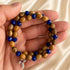 Bracelet held in hand: olive wood and dark blue faceted beads with silver cross charm