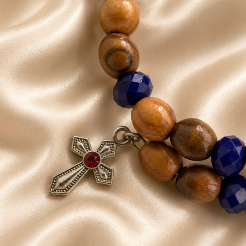 Beaded wrap bracelet close-up with olive wood beads, dark blue crystals, and silver cross charm