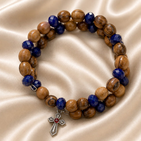 Beaded wrap bracelet laid flat with olive wood spheres and dark blue faceted beads, cross charm