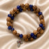 Beaded wrap bracelet laid flat with olive wood spheres and dark blue faceted beads, cross charm