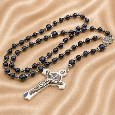 A rosary with dark navy blue stone beads and silver metal accents, including a silver crucifix.