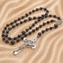 A rosary with dark navy blue stone beads and silver metal accents, including a silver crucifix.