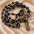 Rosary with dark navy blue lapis lazuli stones and silver-toned metal beads, featuring a silver crucifix and medallion.