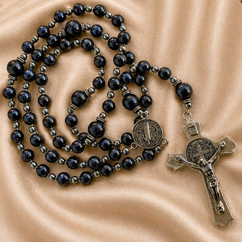 Rosary with dark blue lapis lazuli-style round beads, small metallic spacer beads, a round medallion, and a silver-toned crucifix.