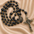 Rosary with dark blue lapis lazuli-style round beads, small metallic spacer beads, a round medallion, and a silver-toned crucifix.