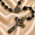 A rosary with dark blue lapis lazuli stones and silver-toned metal beads, featuring a St Benedict medallion and a crucifix.