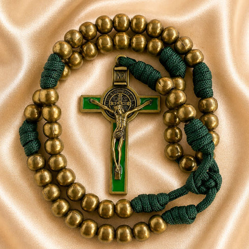 A rosary with gold-toned metal beads, a green and gold St Benedict cross, and dark green knotted cord accents.