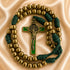 A rosary with gold-toned metal beads, a green and gold St Benedict cross, and dark green knotted cord accents.