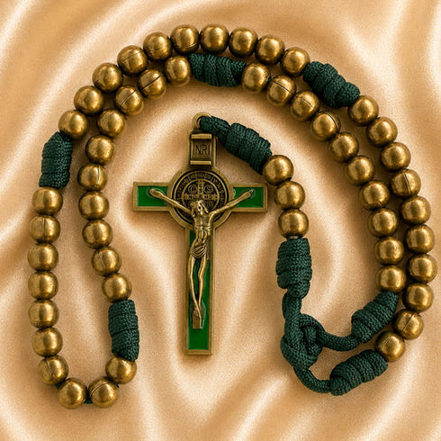 A Catholic rosary with bronze metal beads, a gold-tone crucifix, and dark green accents, on a beige fabric background.
