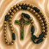 A Catholic rosary with bronze metal beads, a gold-tone crucifix, and dark green accents, on a beige fabric background.