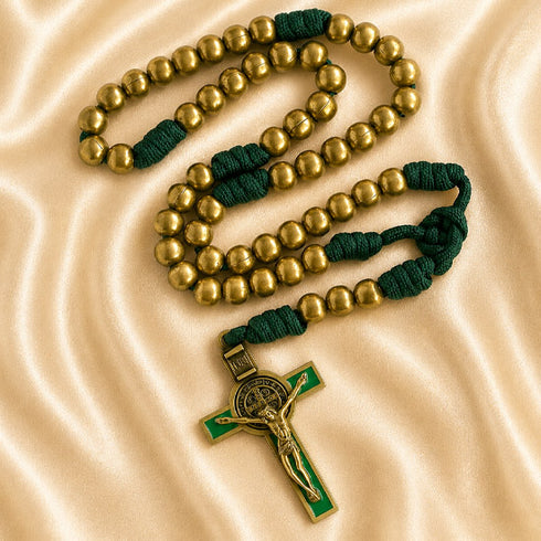 A Catholic rosary with gold-tone metal beads, dark green knotted cord, and a crucifix with a green enamel background.
