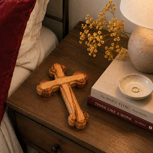 Wooden cross on a nightstand with a book and decorative elements