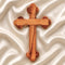 Hand-crafted olive wood budded cross from Bethlehem with carved edges, laid on white surface.