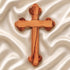 Hand-crafted olive wood budded cross from Bethlehem with carved edges, laid on white surface.