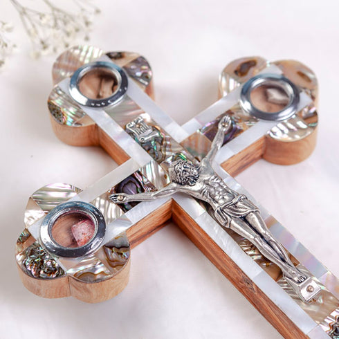 Handmade olive wood cross with silver crucifix, mother of pearl inlay, laid on white cloth