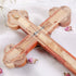 Back of a budded olive wood cross with crucifix and the word "Jerusalem", lying on white background with rose petals.