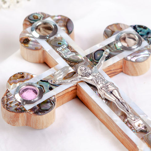 Detailed mage of a budded olive wood cross on a white background, featuring a silver crucifix, white and green mother of pearl accents, and the Four Elements capsules.
