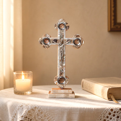 Decorative cross on a table with a candle and book in a warm setting