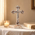 Decorative cross on a table with a candle and book in a warm setting