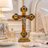 Decorative cross with religious figure, Chanel perfume bottle, and jewelry on a table.
