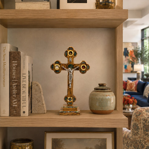 Decorative cross on a shelf with books and a ceramic jar in a home setting