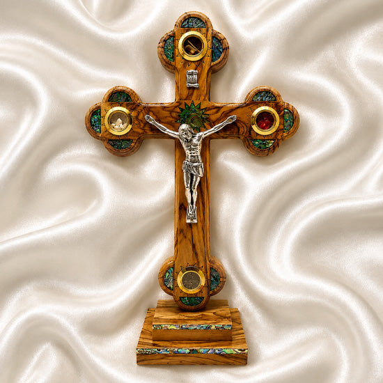Decorative cross with a figure on a stand against a white textured background
