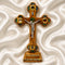 Decorative cross with a figure on a stand against a white textured background