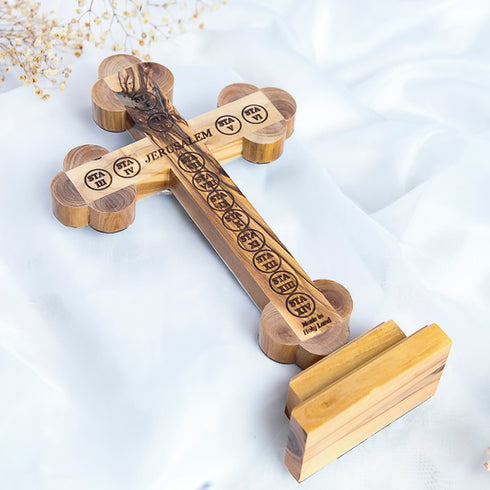 Detailed image of a budded handcrafted standing olive wood cross with back engraving of the Stations of the Cross, photographed on a white background.