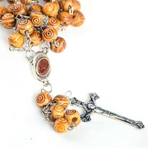 Packshot of olive wood rosary with carved beads and Holy Soil emblem centerpiece and silver crucifix.