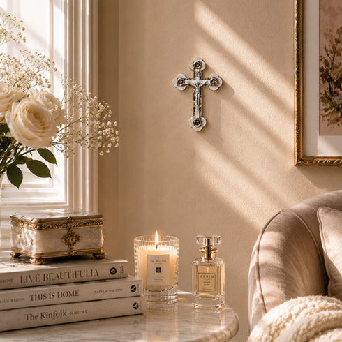 Decorative setting with books, candle, and perfume bottle on a table next to a couch.