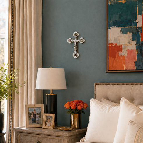 Nursery room with gray walls, a lamp, framed photos, and a vase of flowers on a dresser.