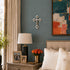 Nursery room with gray walls, a lamp, framed photos, and a vase of flowers on a dresser.