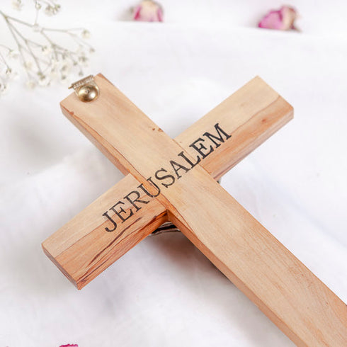 Handmade Catholic cross with "Jerusalem" written on the back, on white background with flowers around it.