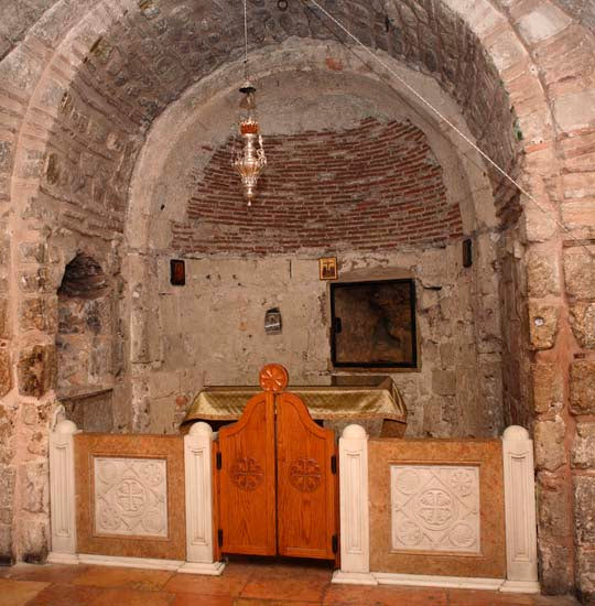 The altar in the Chapel of Adam and a glass-covered window reveals the cracked bedrock of Golgotha.
