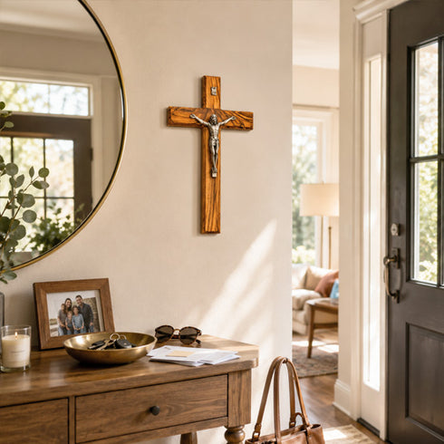 Wooden cross on a wall above a wooden console table with decor items.