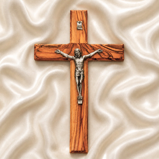 Wooden cross with a silver Jesus figure on a white fabric background