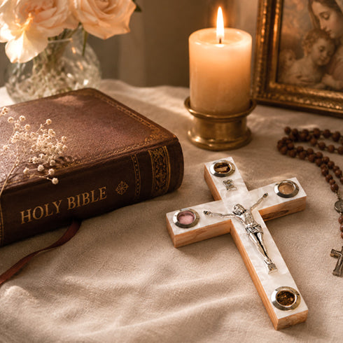 Cross, Holy Bible, candle, and rosary on a textured surface with a blurred background
