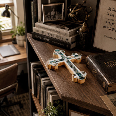Budded cross resting on a busy wooden shelf