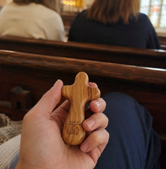 Hand holding a wooden cross in a church setting