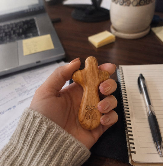 Hand holding a wooden keychain with a desk in the background