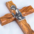 Close-up of a handmade olive wood cross with metal Boy Communion emblem on white background.