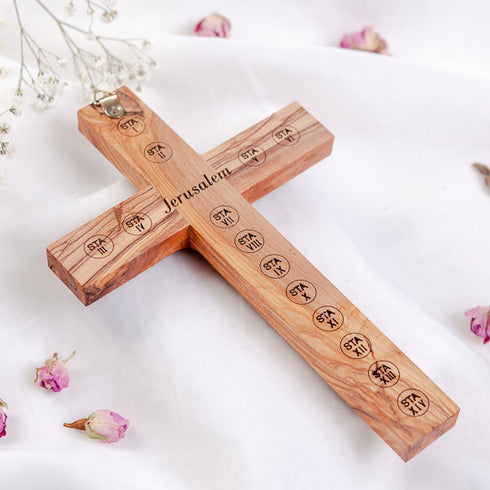 Back of a hand-carved olive wood cross with Stations of Cross and "Jerusalem" engraved, on a white surface.