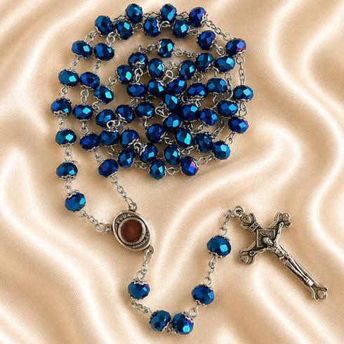 Blue crystal rosary with faceted beads, Jerusalem holy soil centerpiece and silver crucifix on champagne satin.