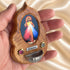 Hand holding a Divine Mercy olive wood holy water font, showing its small size and devotional details