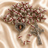 A silver-toned rosary with red enamel accents, featuring a central heart-shaped medallion with a religious image and a crucifix.