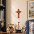 Decorative items including a teddy bear, sailboat, and clock on a shelf with a cross and framed picture in the background.