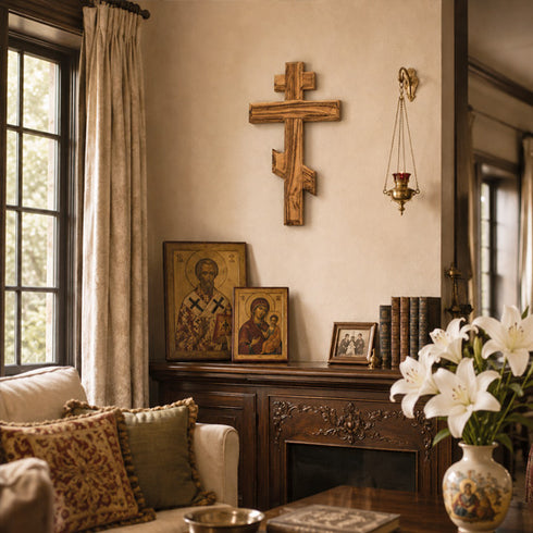 Orthodox style living room with decorative cross, icons, and flowers on a table.