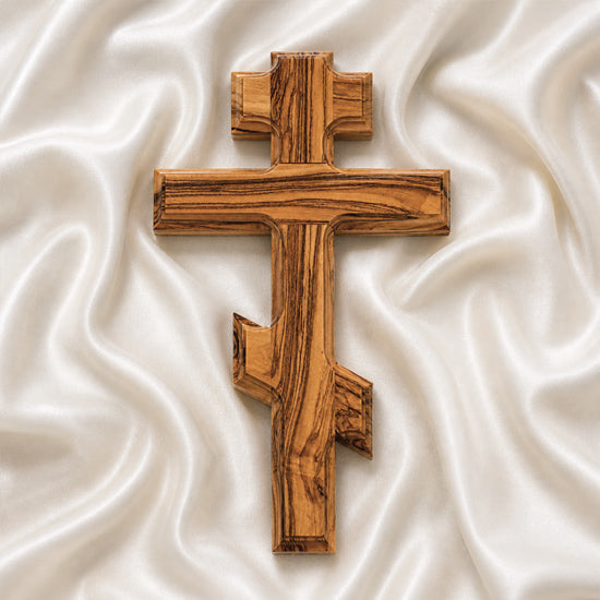 Wooden Orthodox cross on a white, textured fabric background