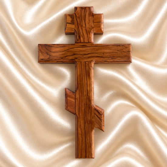 Wooden Orthodox cross on a white, textured fabric background