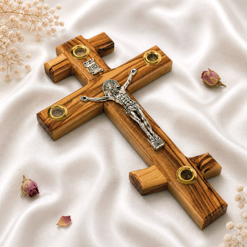 Wooden cross with a silver Jesus figure on a white fabric background